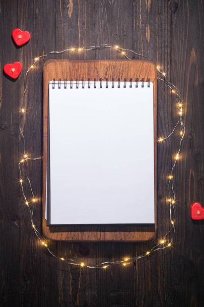 Cuaderno en blanco, rodeado de pequeñas luces y corazones pequeños, ideal para maqueta
 - Foto, imagen