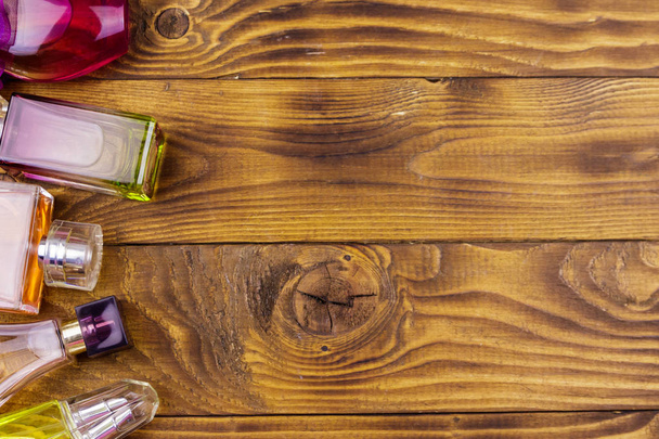 Different bottles of perfume on the wooden background. Top view - Photo, Image