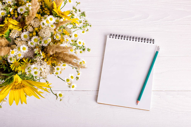 Bouquet of flowers, notebook and pencil on a white table. Copy space. - Foto, Imagen