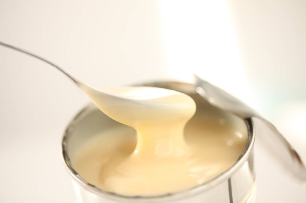 gezoete gecondenseerde melk met lepel - Foto, afbeelding