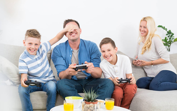 Ευτυχισμένος νέος οικογένεια παίζοντας βιντεοπαιχνίδια στην τηλεόραση. - Φωτογραφία, εικόνα