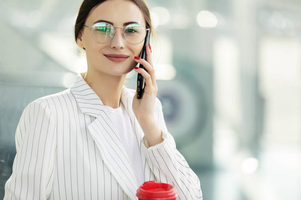 Ділова жінка з кавою і розмовляє по телефону біля офісу
 - Фото, зображення