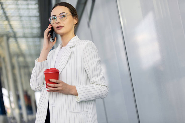 Business woman with coffe and talking on the phone near office - Photo, Image