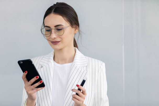 Cropped image of successful business woman wearing suit using modern smartphone - Photo, image