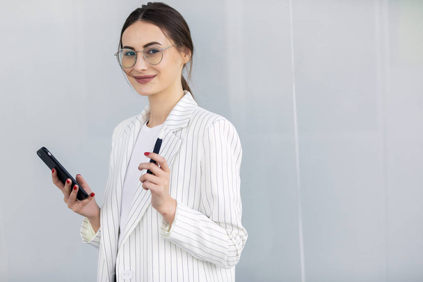 Cropped image of successful business woman wearing suit using modern smartphone - 写真・画像