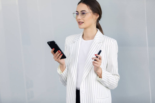 Cropped image of successful business woman wearing suit using modern smartphone - Foto, afbeelding