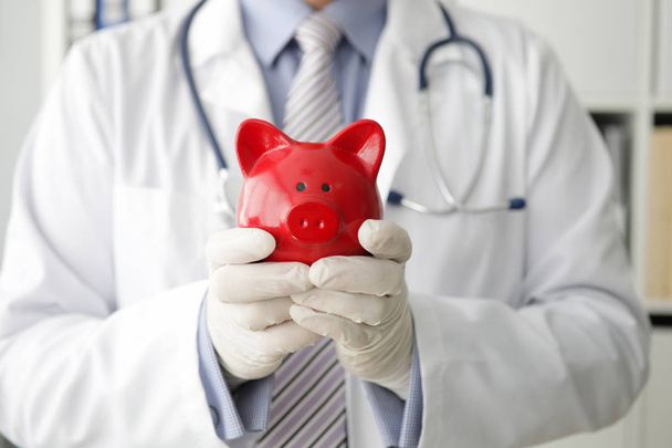 Doctor holding piggy bank - Foto, immagini
