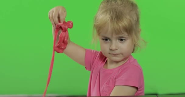 glückliches kleines Mädchen spielt mit Knetmasse auf Chroma-Schlüsselhintergrund - Filmmaterial, Video