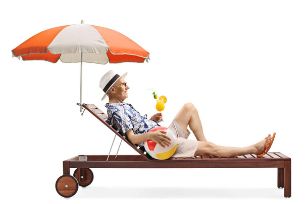 Senior man on a sunbed with a ball and a cocktail - Zdjęcie, obraz