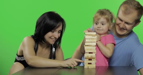 Moeder, vader en dochter spelen jenga. Trekt houten blokken van de toren - Video
