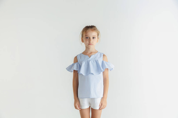 Маленька усміхнена дівчинка позує в повсякденному одязі на білому фоні студії
 - Фото, зображення