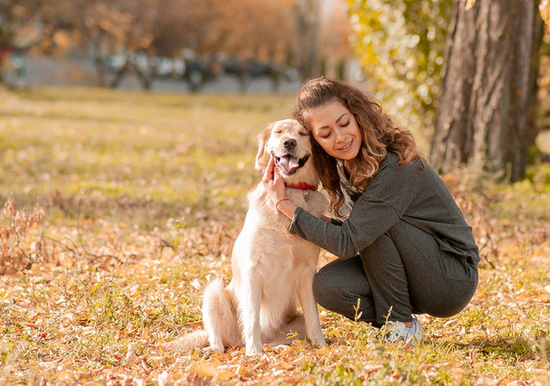Mooie lachende vrouw met leuke golden retriever hond - Foto, afbeelding