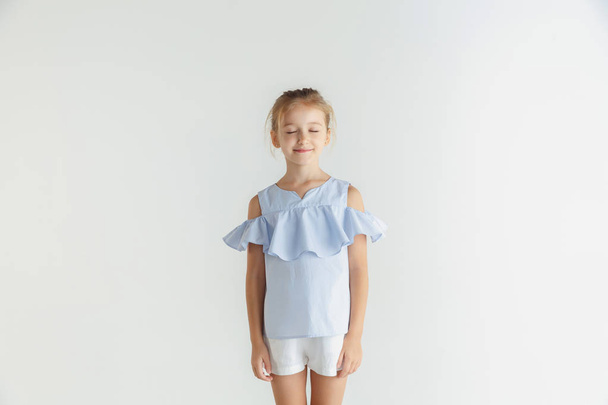 Little smiling girl posing in casual clothes on white studio background - Foto, afbeelding