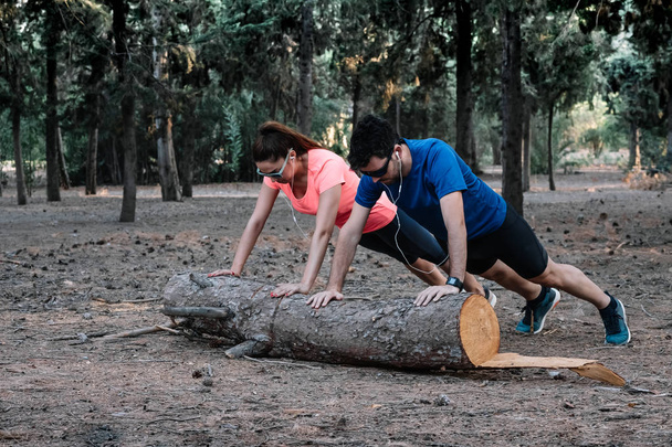 couple doing push-ups on a log in a park - Photo, Image