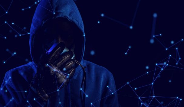 hacker with blue hood outfit with mask glove on background in security virus network and ai robotic concept, data deep learning, server secure hacking - Zdjęcie, obraz