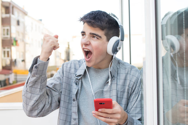 başarıyı kutlayan cep telefonu ve kulaklık ile genç öforik - Fotoğraf, Görsel