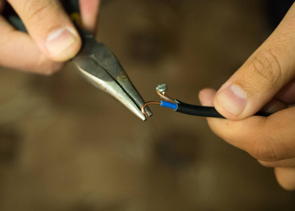 Réparation de l'alimentation électrique par pliage des fils à l'aide de pinces rondes
 - Photo, image