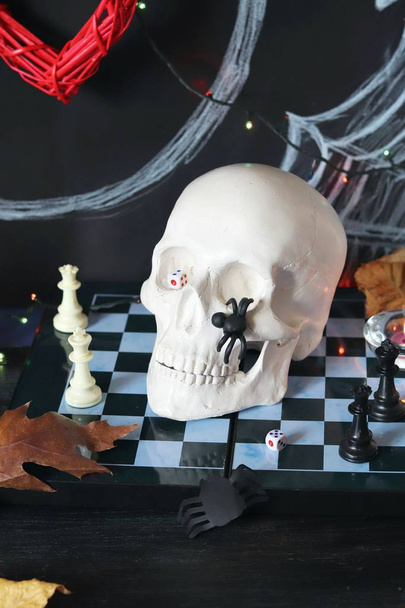 Composição decorativa para decoração de interiores para Halloween, crânio, velas em chamas, decoração, folhas de outono, iluminação sobre um fundo preto com a inscrição 31 de outubro
 - Foto, Imagem
