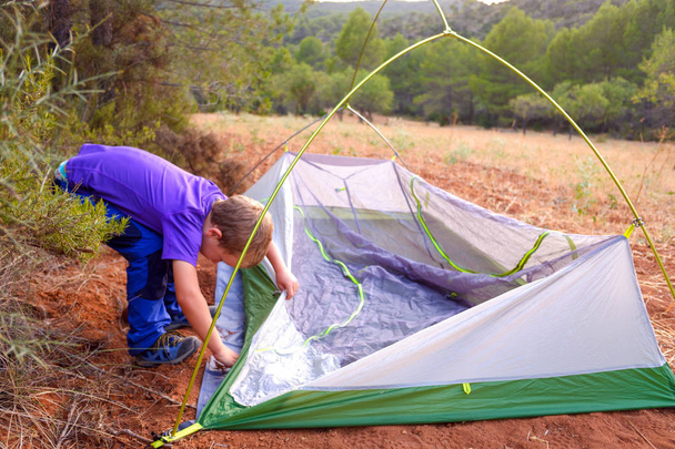 Leirintäpoika valmistelee telttaa yöpymään metsässä
, - Valokuva, kuva