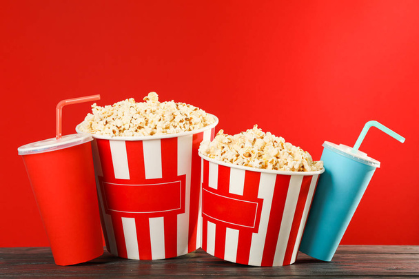 Popcorn kauhat ja paperimukeja vastaan punainen tausta, tilaa
 - Valokuva, kuva