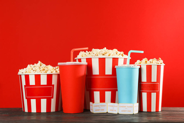 Popcorn buckets, paper cups and tickets against red background,  - 写真・画像