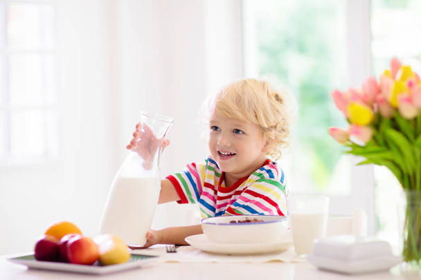 Çocuk kahvaltı yapıyor. Süt ve tahıl ile çocuk. - Fotoğraf, Görsel