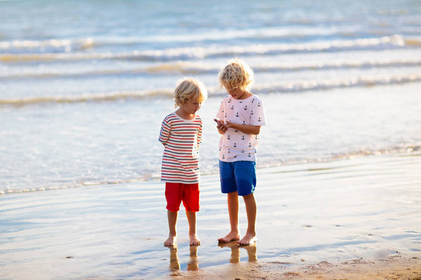 Τα παιδιά παίζουν σε τροπική παραλία. Παιχνίδια άμμου και νερού. - Φωτογραφία, εικόνα