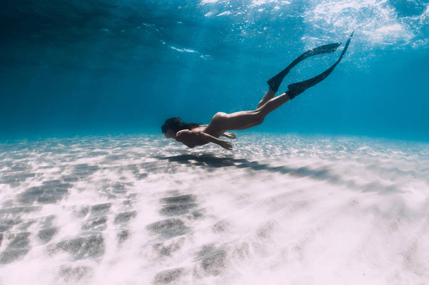 Naked woman free diver glides over sandy sea with fins. Freedivi - Foto, Imagen