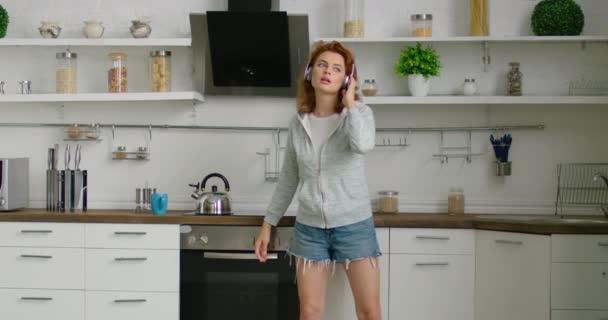 Young pretty woman is dancing and singing in her new kitchen - Felvétel, videó