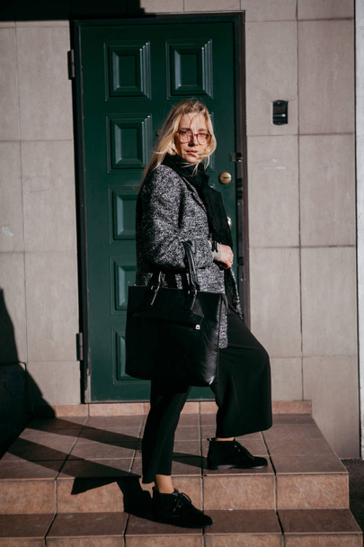 Stylish blonde stands on  steps in front of green door - Foto, Bild
