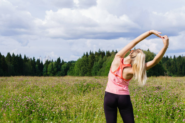 fiatal nő csinál gyakorlatokat nyúlik a réten kívül c - Fotó, kép