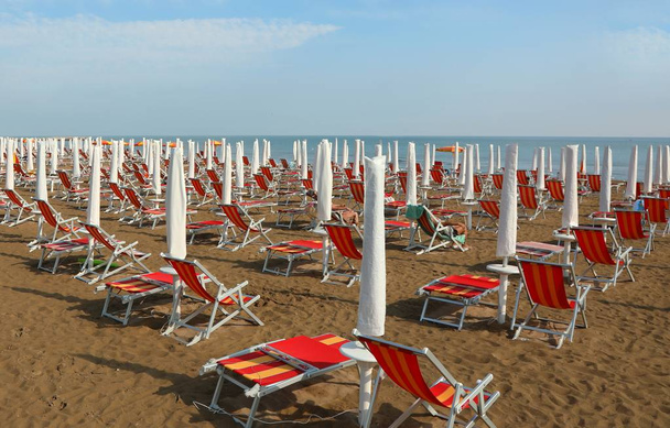 napernyők és nyugágyak az üdülőhely homokos strandján - Fotó, kép