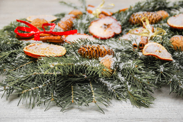 Szilveszteri ünnep dekorációk. Handmade Karácsonyi koszorú fenyő ágak diófélék, fahéj és szárított gyümölcsök leporolta a mesterséges hó. Alakformálás - Fotó, kép