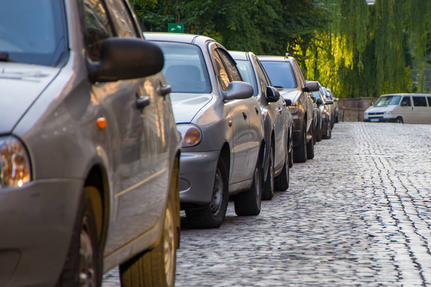 Zaparkowane samochody w europejskim mieście wzdłuż brukowanej chodnika, opuszczona ulica w mieście - Zdjęcie, obraz