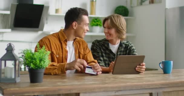 alegre pareja mixta están haciendo compras en línea en la cocina
 - Metraje, vídeo