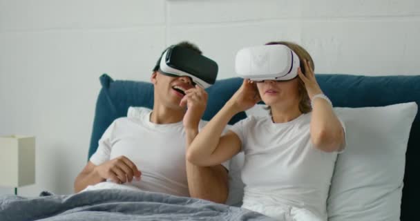 Gemengd paar ontspannen in bed, kijken naar 360 video in Virtual Reality Headsets - Video