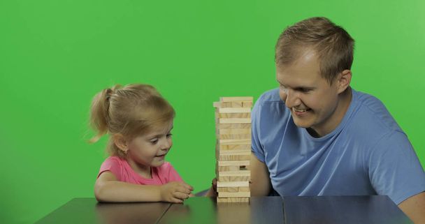 Apa és lánya játszik a Jenga. Kisgyermek húz fából készült blokkok torony - Fotó, kép