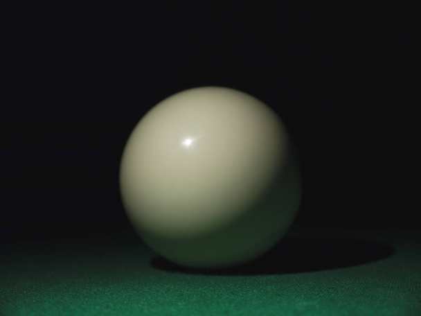 Λευκή μπάλα σε ένα τραπέζι μπιλιάρδου στο σκοτάδι - Φωτογραφία, εικόνα