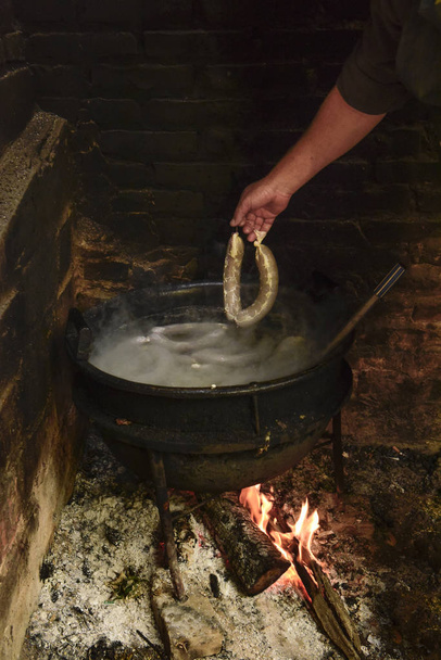 Приготування білих кров'яних ковбас у залізній каструлі
 - Фото, зображення
