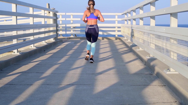 Fiatal Runner nő fut a strandon naplementekor, kitartást edzés. Lassított mozgás. - Felvétel, videó