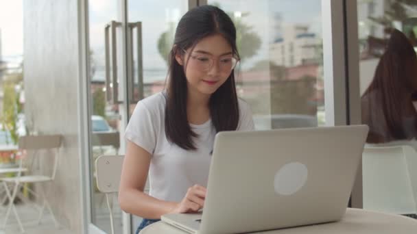 Mulheres asiáticas freelance trabalhando em laptop na cafeteria. Jovem empresa da Ásia Menina usando o computador para o comércio, envie e-mail, trabalho digital na internet na mesa no café ao ar livre no conceito da noite. Movimento lento
 - Filmagem, Vídeo