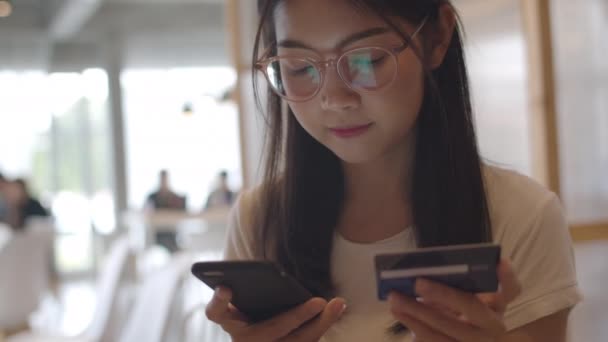 Свободные азиатские женщины делают покупки в офисе. Молодая японская девушка азиатского происхождения, пользующаяся мобильным телефоном, кредитной картой, покупает и покупает электронную коммерцию в Интернете на столе на рабочем месте. Медленное движение
. - Кадры, видео