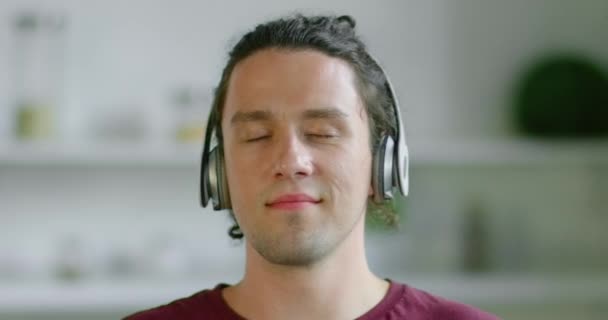 Ο νεαρός άντρας βγάζει το ασύρματο ακουστικό του, θαμπό φόντο - Πλάνα, βίντεο