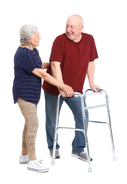 Elderly woman helping her husband with walking frame on white background - Photo, image