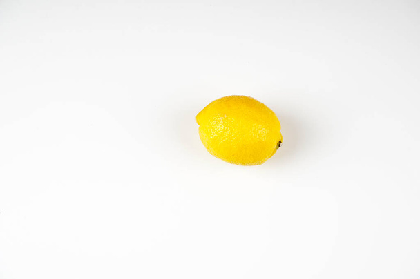 one whole yellow lemon on white table surface  - Zdjęcie, obraz