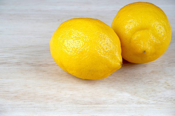 whole yellow lemons on light wooden table surface  - Φωτογραφία, εικόνα