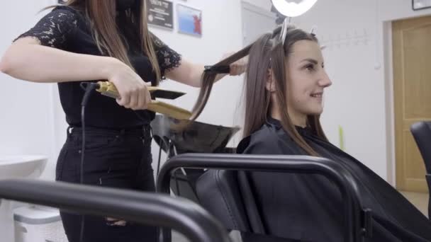 parrucchiere rende laminazione dei capelli in un salone di bellezza per una ragazza con i capelli castani. concetto di cura dei capelli
. - Filmati, video