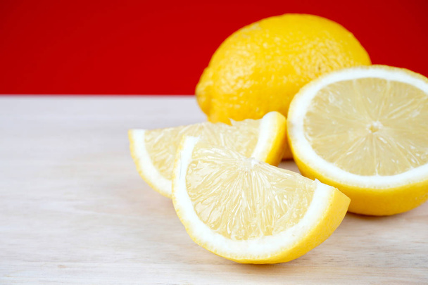 white wooden table with lemons parts against red wall background   - Фото, зображення