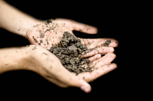 Close up of hands of a farmer holding new fresh soil after rain in his hands and showing to the camera. - Fotografie, Obrázek