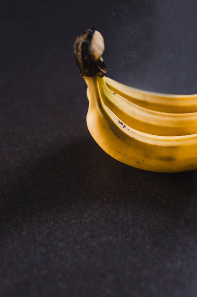 three bananas on dark background shot at shallow depth of field - Fotó, kép